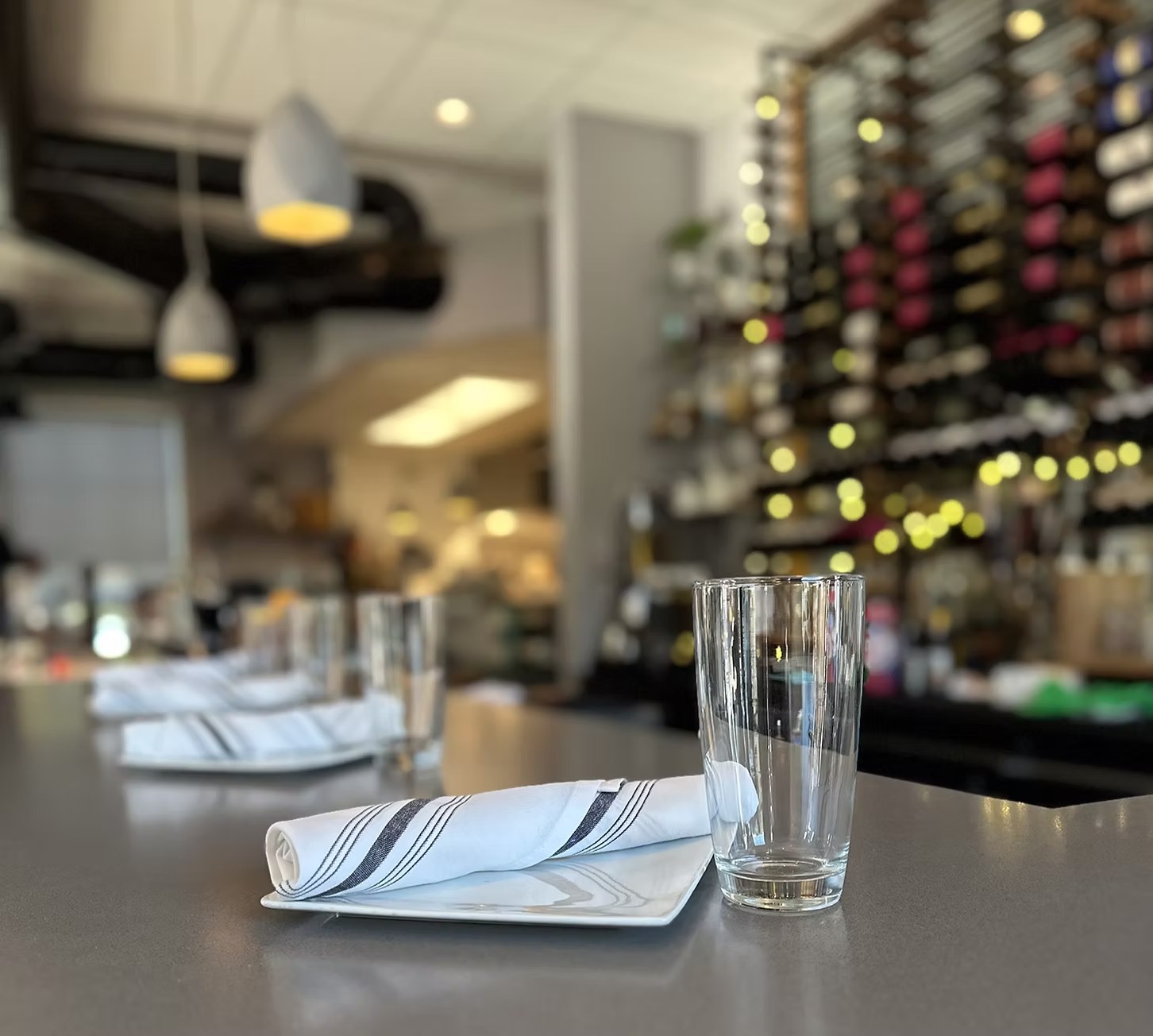 Napkin and glass on the counter, wine wall behind