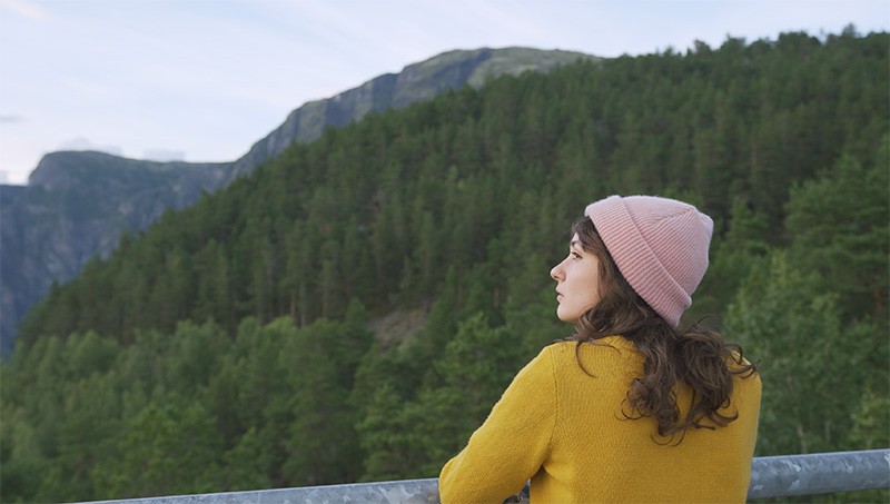 Woman in a pink beanie looking out over a forested valley